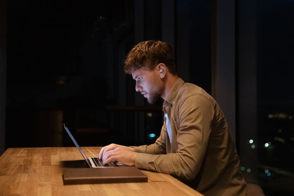 man sitting in a dark room with laptop
